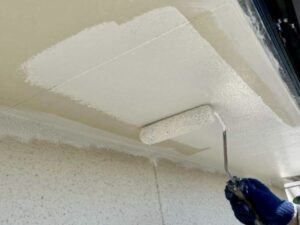 ローラーで軒天井に白色塗料を丁寧に塗り広げる作業